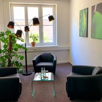 Coaching- und Mediationsraum: 3 Sessel, ein Tischchen, eine große Lampe, Pflanzen, Bilder an den Wänden